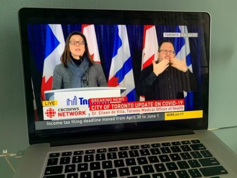 Laptop showing news conference about COVID-19 featuring ASL translation